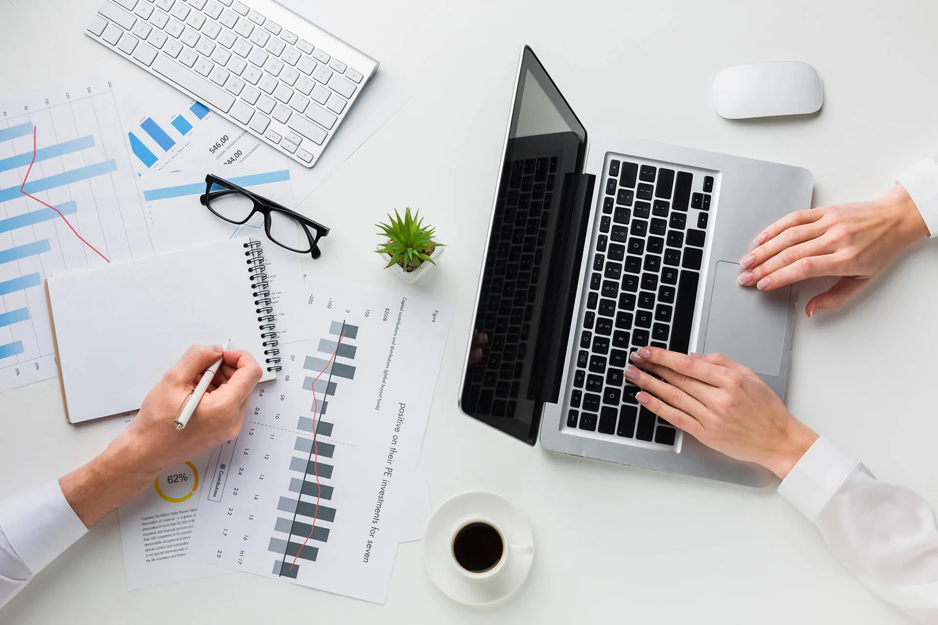 Woman hands writing on report near laptop on white office desk top view